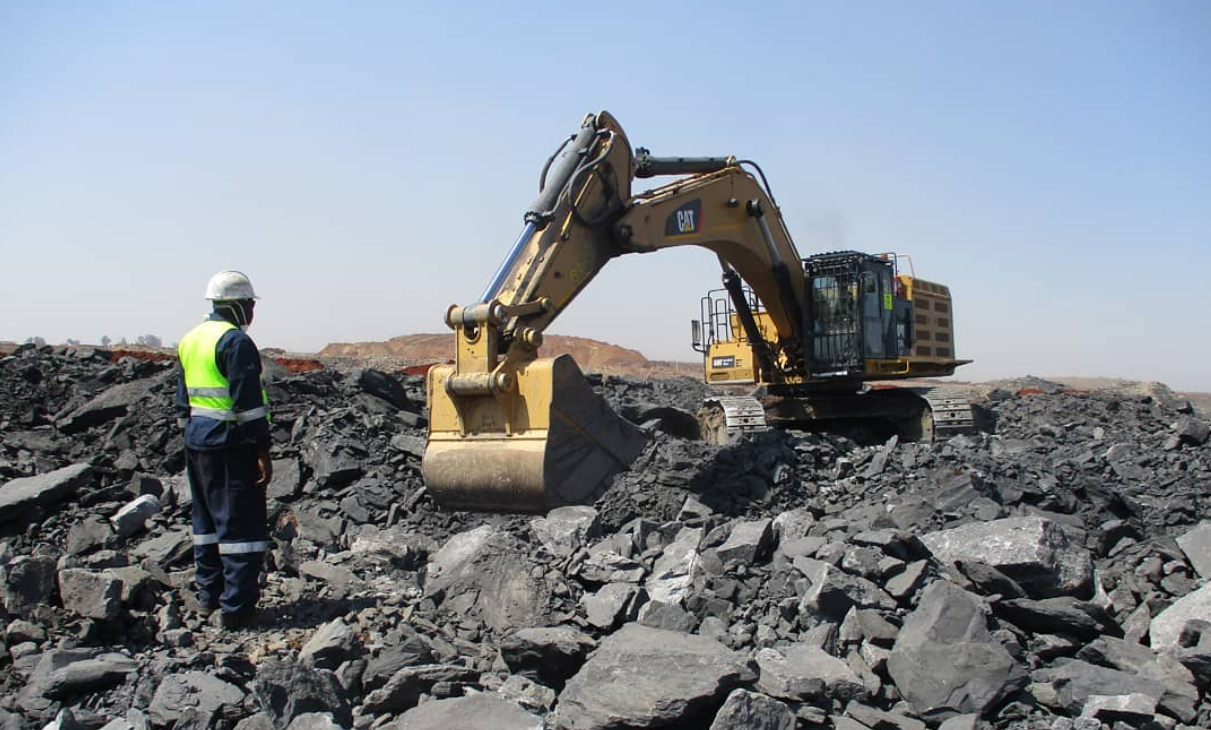 Excavator and a worker among rocks at a Mphakama worksite
